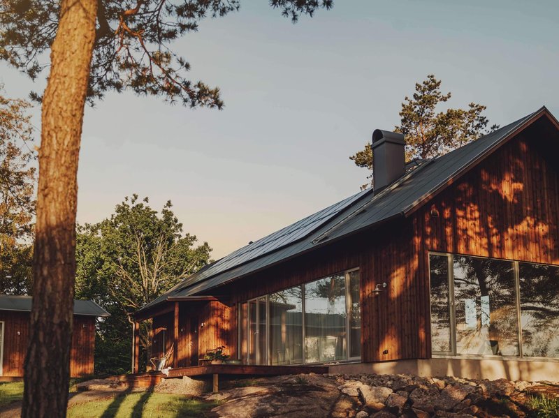 Solcellspaneler installerade på ett tak till en röd stuga