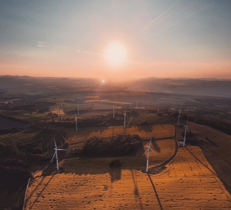 Landschaft mit Sonnenuntergang und Windrädern.
