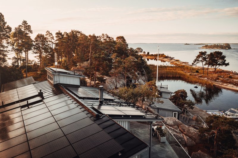 Auf Photovoltaik setzen und so das Klima schützen (Haus am See mit PV-Anlage auf dem Dach)